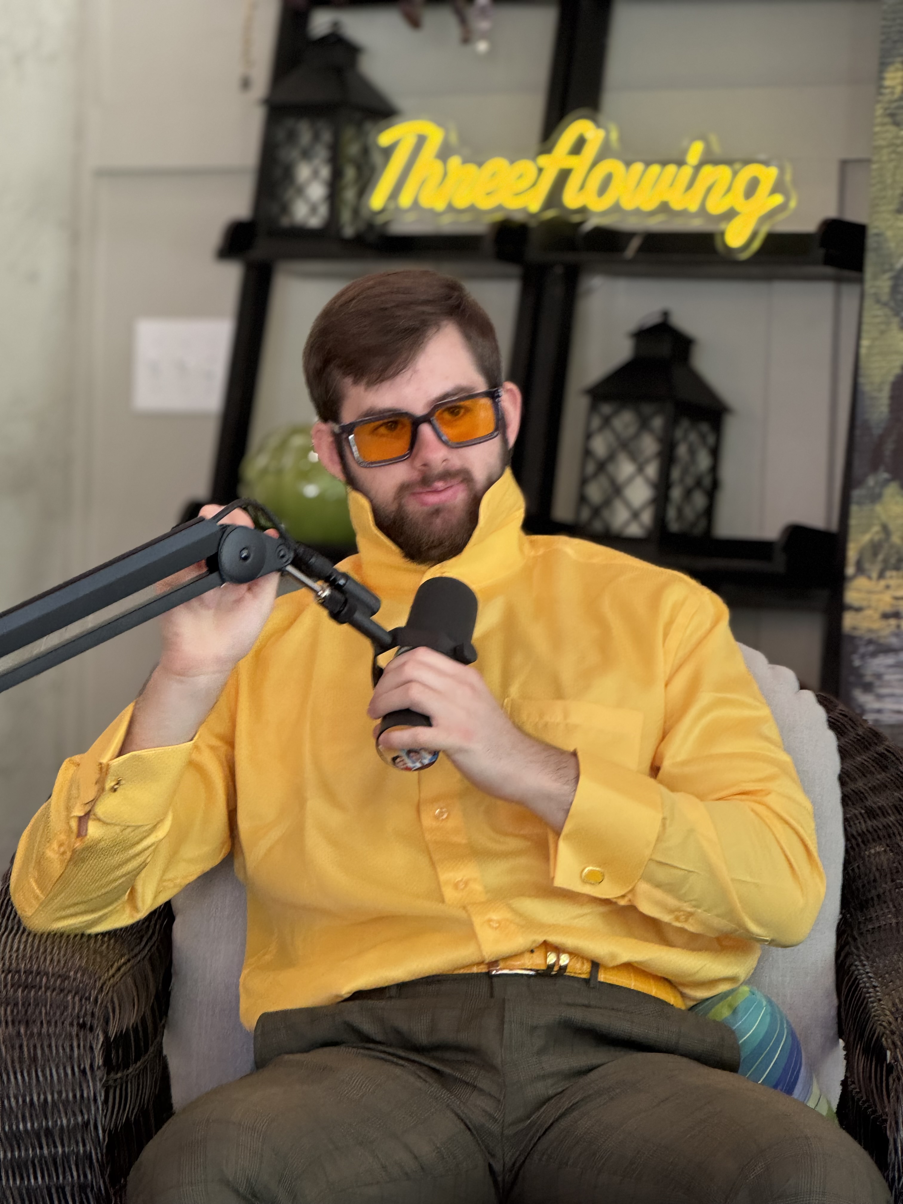 Ethan in the podcast studio with yellow shirt and microphone