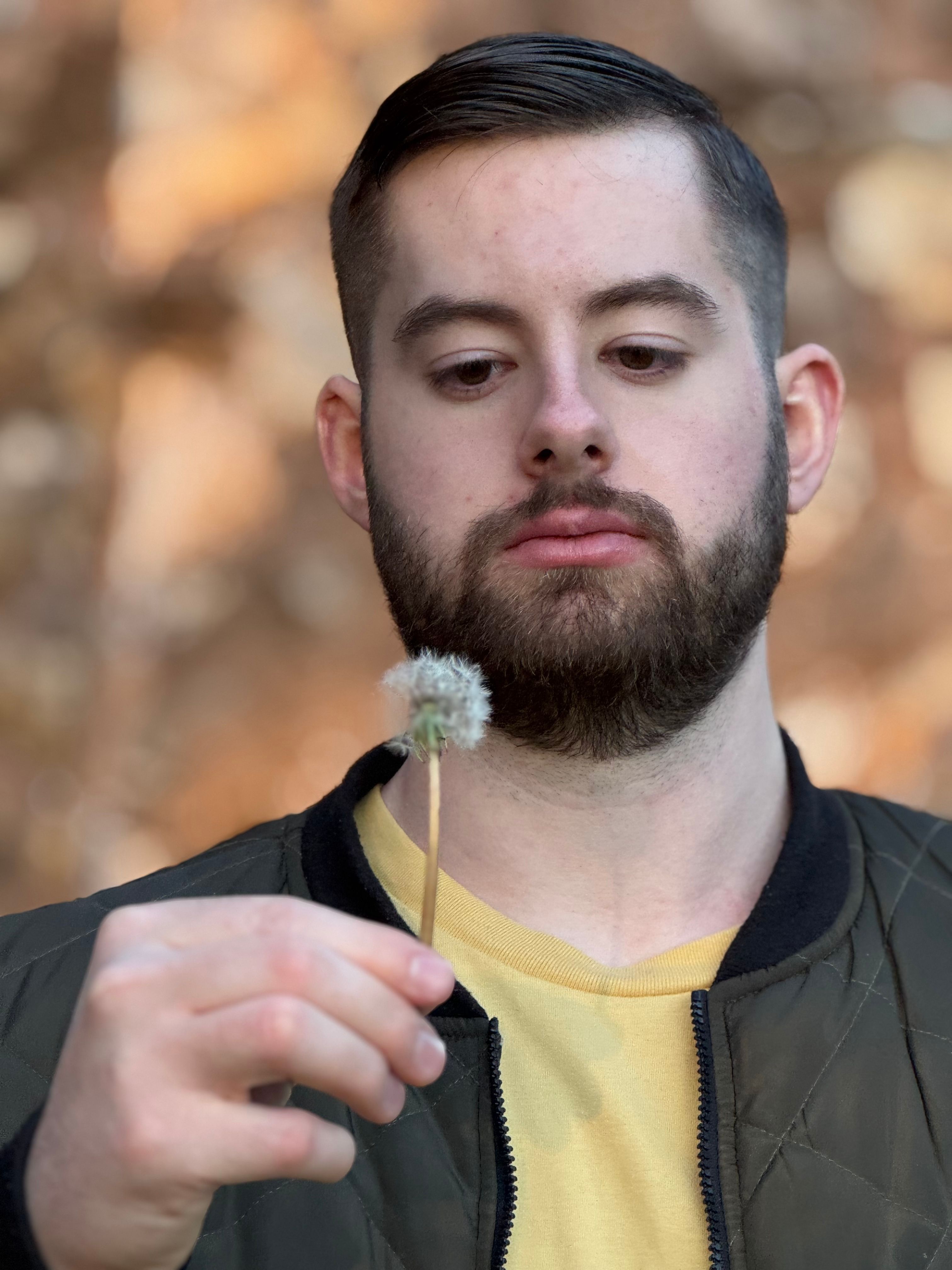 Ethan holding a dandelion in green jacket